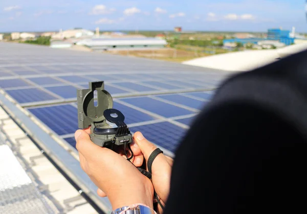 Hand Holding Compass at Solar Rooftop System Importance of Direction Concept