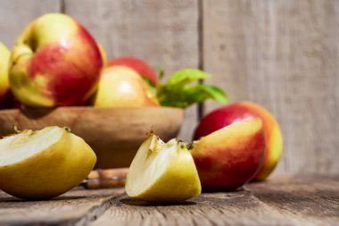 Ahşap eski bir masada yeşil yaprakları ile taze kırmızı elma. Dilimlenmiş elma ile ahşap bir arka plan üzerinde. Metin için boş alan. yumuşak odak
