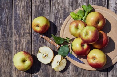 Ahşap eski bir masada yeşil yaprakları ile taze kırmızı elma. Dilimlenmiş elma ile ahşap bir arka plan üzerinde. Metin için boş alan. yumuşak odak