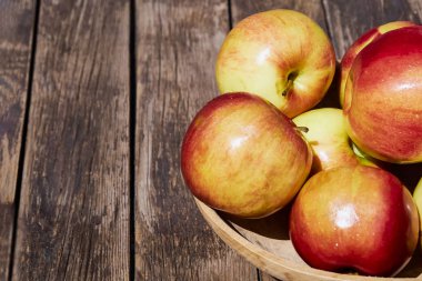 Ahşap eski bir masada yeşil yaprakları ile taze kırmızı elma. Ahşap bir arka plan üzerinde. Metin için boş alan. yumuşak odak