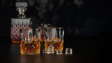 Güçlü alkol, buz ile viski için bardak, koyu bir antika ahşap masa ve siyah arka plan üzerinde durmak, kopya alanı