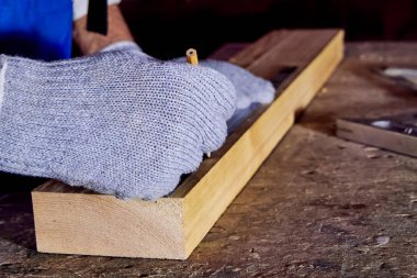 Marangoz marangoz atölyesinde ahşap işleme makineleri üzerinde çalışır. Bir adam ağaçla çalışır.