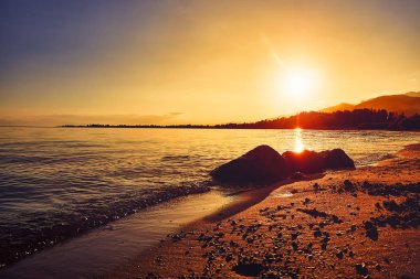 Gün batımında plajın güzel panoramik manzarası, güzel büyük dağların arka planında akşam güneş ışığı ile aydınlatılmış, lüks yaz maceraları, açık hava etkinlikleri, turizm