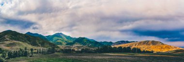Yazın bir dağ vadisi manzarası, bulutlu bir gökyüzü. Dağ tepelerinin üzerinde peri masalı günbatımı, inanılmaz doğa, dağlarda yaz. Seyahat et. Doğanın güzel arkaplan resmi