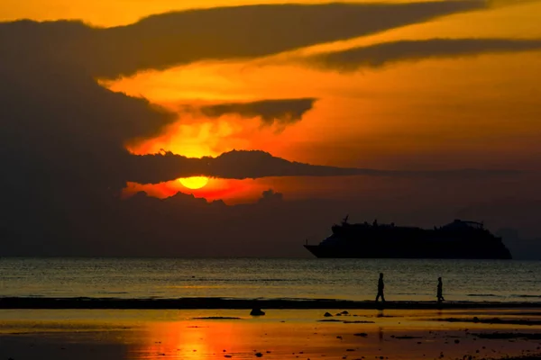 Siluet gemisi okyanus ve deniz, kum banka üzerinde yürüyen insanlar, harika gün batımı alacakaranlık gökyüzü arka plan bulut