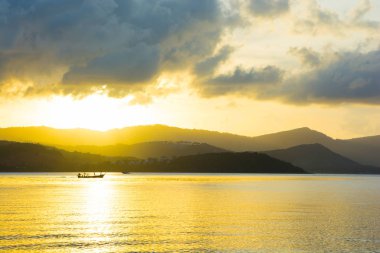 Sakin deniz suyu üzerinde ışık yansıtan güzel altın ışık gökyüzü bulut günbatımı adanın, yukarıda
