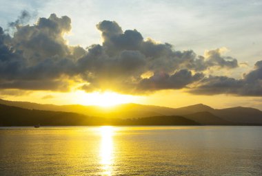 Sakin deniz suyu üzerinde ışık yansıtan güzel altın ışık gökyüzü bulut günbatımı adanın, yukarıda