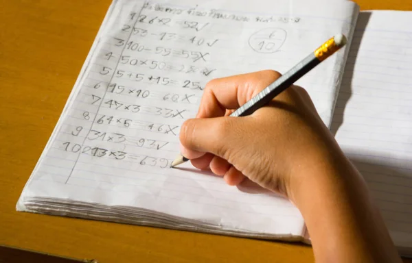Matematik ödevini okuldan üzerinde kalem yazılı cevap tutan çocuğun el
