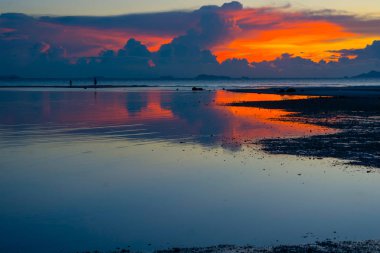 Dramatik akşam alacakaranlık gökyüzü bulut su düşük gelgit denizde, ada plaj sahil silüeti yürüyüşe kum banka üzerinde kişi ile