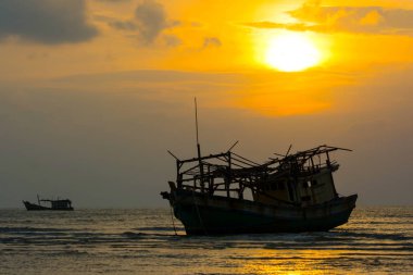 Siluet balıkçı tekne kazası düşük Tide Seaside, harika parlayan güneş alacakaranlık gökyüzü bulut içinde geçmiş, üzerinde karaya oturdu