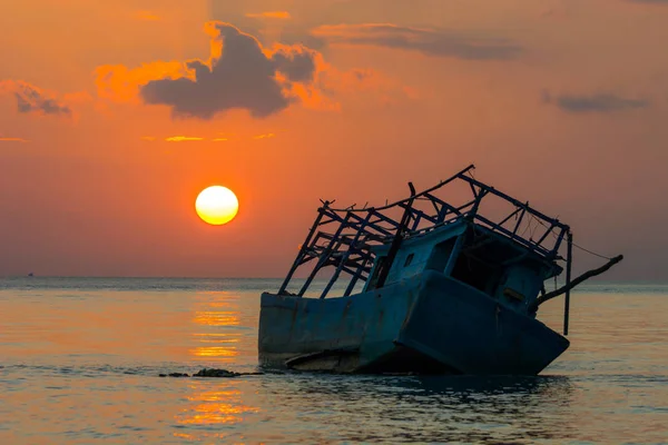 Siluet balıkçı tekne kazası karaya sığ su kum, deniz, günbatımı zamanı, dramatik ışıklık bulut okyanus arka planda yukarıda