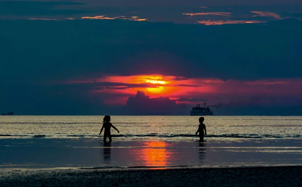 Двое Детей Играют Низком Приливном Море Драматические Два Солнца Закате — стоковое фото