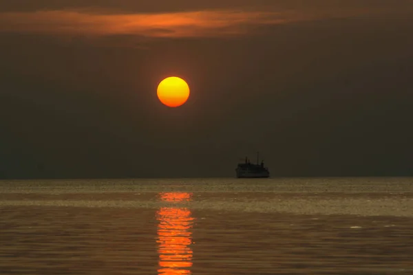 Alacakaranlıkta gökyüzü günbatımı, su üzerinde ışık yansıtan, alacakaranlık karanlık bulut feribot tekne arka planda yukarıda