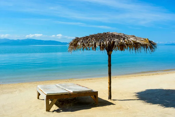 Kuru ot çatı şemsiye ve plaj kum deniz güneşli gün, mavi gökyüzü bulut ada arka planda yukarıda, yatağa