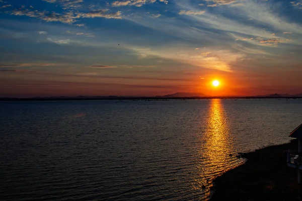 Mavi gökyüzü güneş doğuyor ve beyaz bulutlar gördüm çok uzak dağ gölge ağarma giden orada güneşin su yüzeyinde bir yansımasıdır.