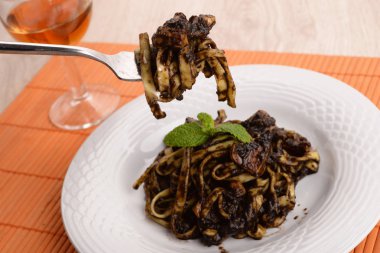Fettuccine beyaz tabak içinde mürekkep balığı ile