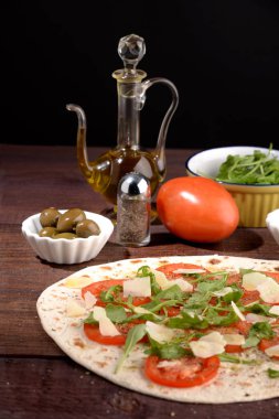 Masanın üzerine peynir sosu ve domatesli roka ile gözleme