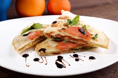 Düz ekmek beyaz tabakta balsamik sirke ile aromalı domates roket ile tepesinde