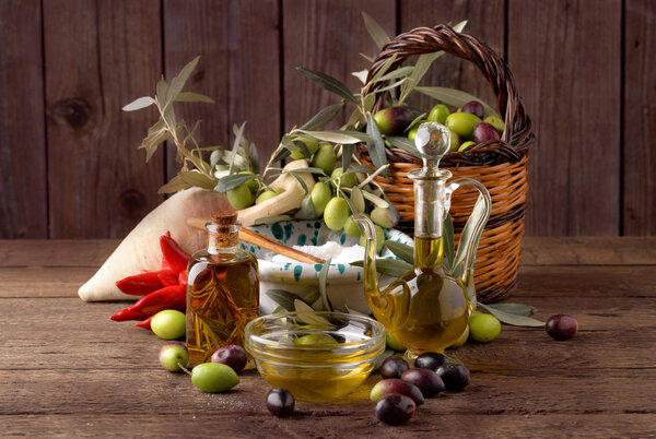 Olives in basket with bottle of oil on wooden table old