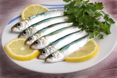 limon dilimleri ve maydanoz ile renkli ahşap arka plan tabakta sardalya
