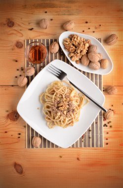 Ahşap masa üzerinde beyaz plaka üzerinde ceviz krem ile fettuccine makarna