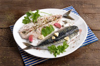 Ahşap masa üzerinde baharatlar ile plaka üzerinde ham filetoların uskumru