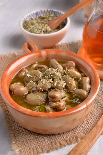 earthenware dish with beans cooked in olive oil and oregano on white table