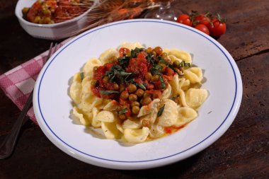 Orecchiette makarna ile bezelye masada beyaz tabakta domates sosu ile