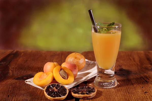 玻璃上的杏子汁和乡村餐桌上的水果 — 图库照片