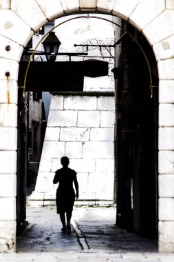 Persona che cammina sotto un arco in controluce