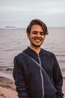 Adam deniz gülümsüyor. Arka planda gemi. Finlandiya Körfezi üzerinden kötü hava.