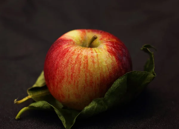 苹果洒在一片叶子上的水和黑色的背景 — 图库照片