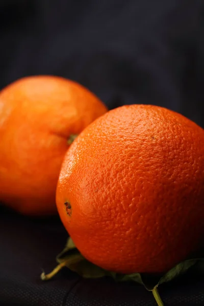 two oranges on leaflets and a black background