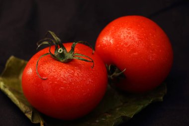 çarşaf ve siyah bir arka plan üzerinde iki kırmızı domates