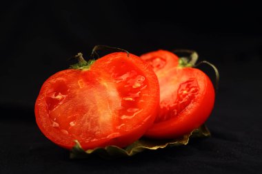 siyah bir zemin üzerine domates iki yarısı