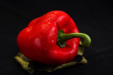 yaprakları siyah bir zemin üzerine kırmızı biber