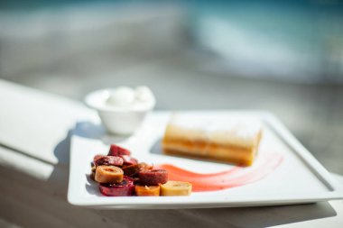 Denizin arka planda bir restoranda beyaz yemek. Çanak tatlı strudel, krema, ev yapımı pastille