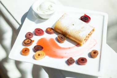 Denizin arka planda bir restoranda beyaz yemek. Çanak tatlı strudel, krema, ev yapımı pastille