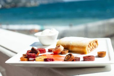 Denizin arka planda bir restoranda beyaz yemek. Çanak tatlı strudel, krema, ev yapımı pastille