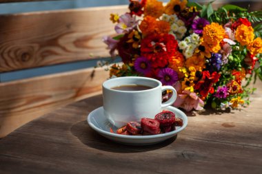 Ahşap bir masa üzerinde kır çiçekleri bir buket arka planda ev yapımı pastille ile kahve ile Beyaz kupa