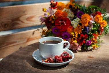 Ahşap bir masa üzerinde kır çiçekleri bir buket arka planda ev yapımı pastille ile kahve ile Beyaz kupa