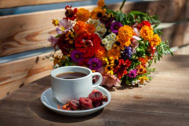 Ahşap bir masa üzerinde kır çiçekleri bir buket arka planda ev yapımı pastille ile kahve ile Beyaz kupa
