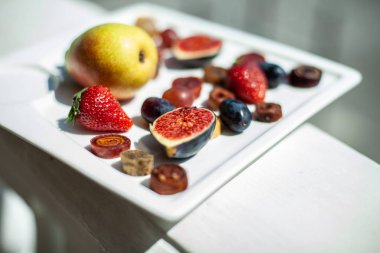 Deniz kıyısının arka planında meyve ve pastille içeren bir tabak. Nefis. Lüks.