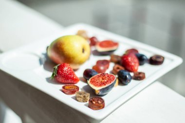 Deniz kıyısının arka planında meyve ve pastille içeren bir tabak. Nefis. Lüks.