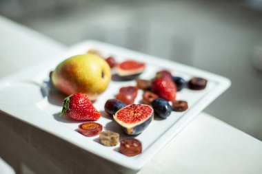 Deniz kıyısının arka planında meyve ve pastille içeren bir tabak. Nefis. Lüks.