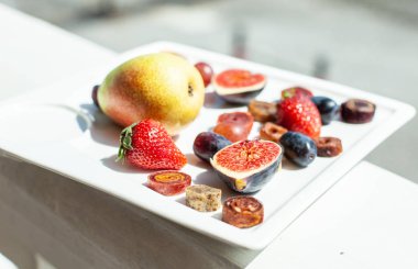 Deniz kıyısının arka planında meyve ve pastille içeren bir tabak. Nefis. Lüks.