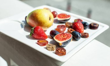 Deniz kıyısının arka planında meyve ve pastille içeren bir tabak. Nefis. Lüks.