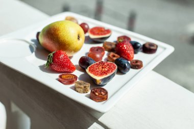 Deniz kıyısının arka planında meyve ve pastille içeren bir tabak. Nefis. Lüks.