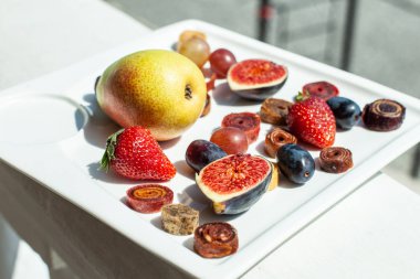 Deniz kıyısının arka planında meyve ve pastille içeren bir tabak. Nefis. Lüks.