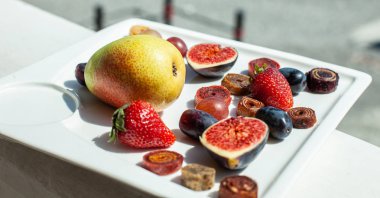 Deniz kıyısının arka planında meyve ve pastille içeren bir tabak. Nefis. Lüks.